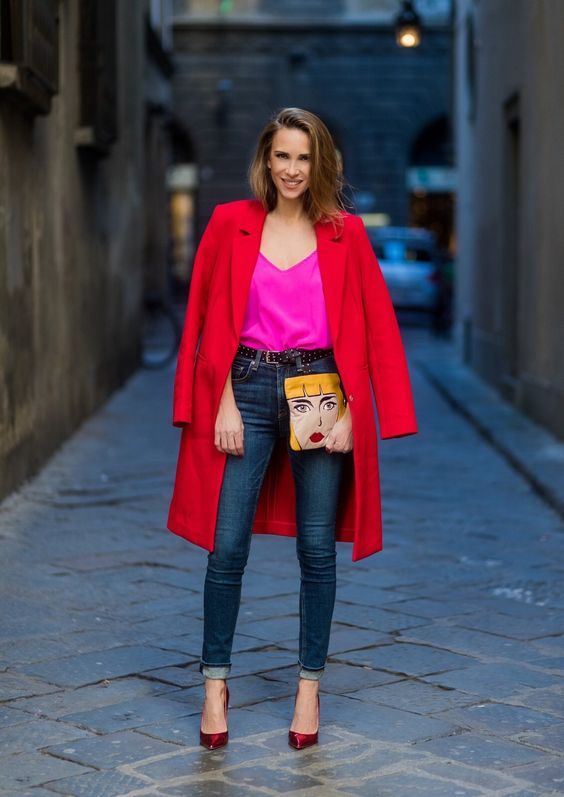 Mujer con outfit compuesto por jean, camisa fucsia y abrigo rojo