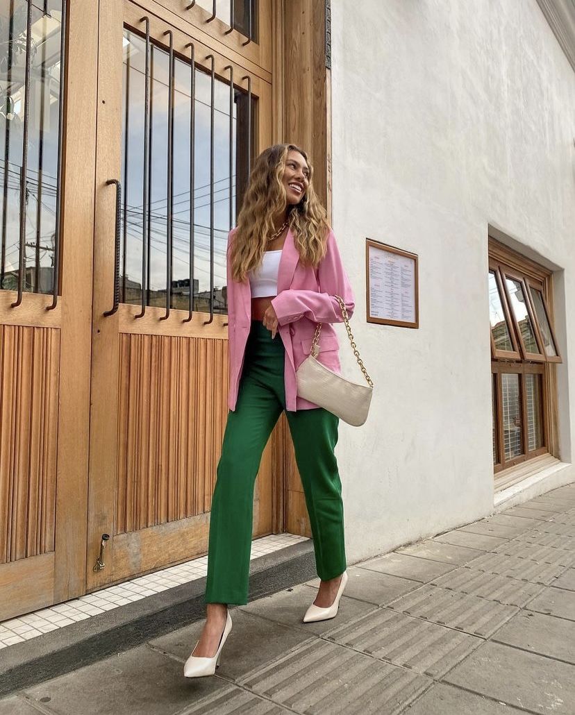 Mujer por la calle con blazer rosa y pantalón verde