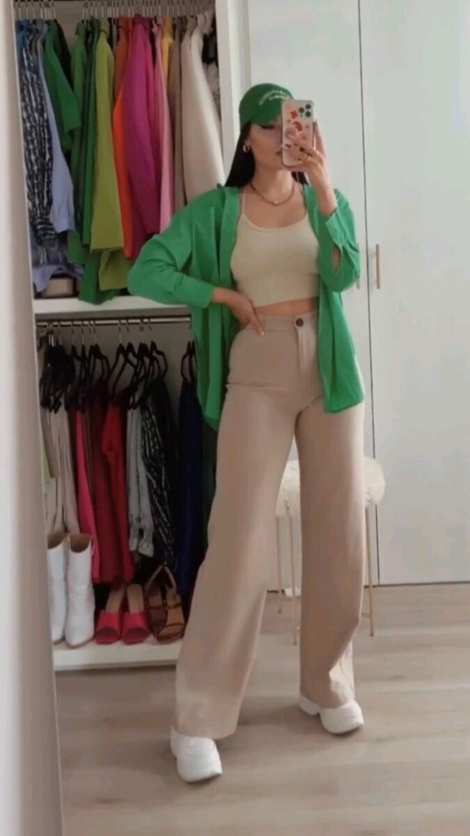 Mujer vistiendo crop top con pantalón beige y blazer verde