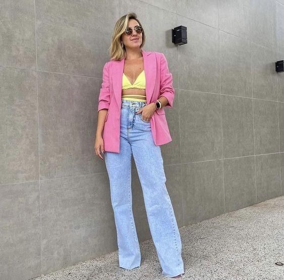 Mujer vistiendo crop top amarillo con blazer rosado y jean